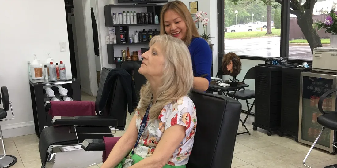 A stylist at Amazing Cuts smiling with a client in the chair inside the Yorktown salon.